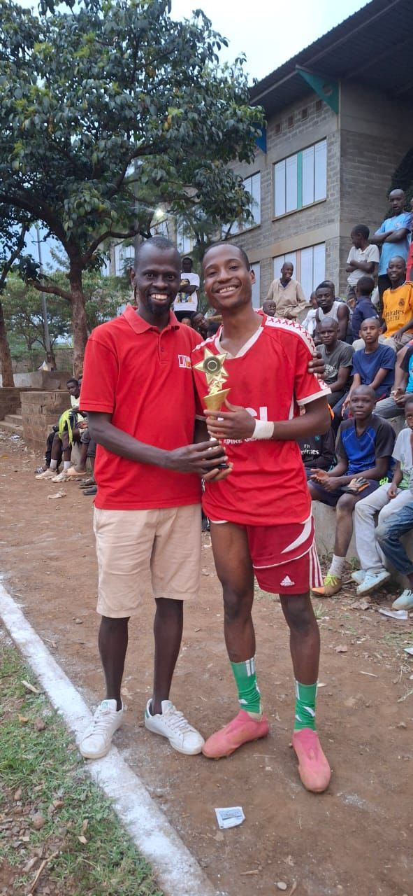 A coach presenting a trophy to a young player at the Inter-Masjid Football Tournament in Kisumu.