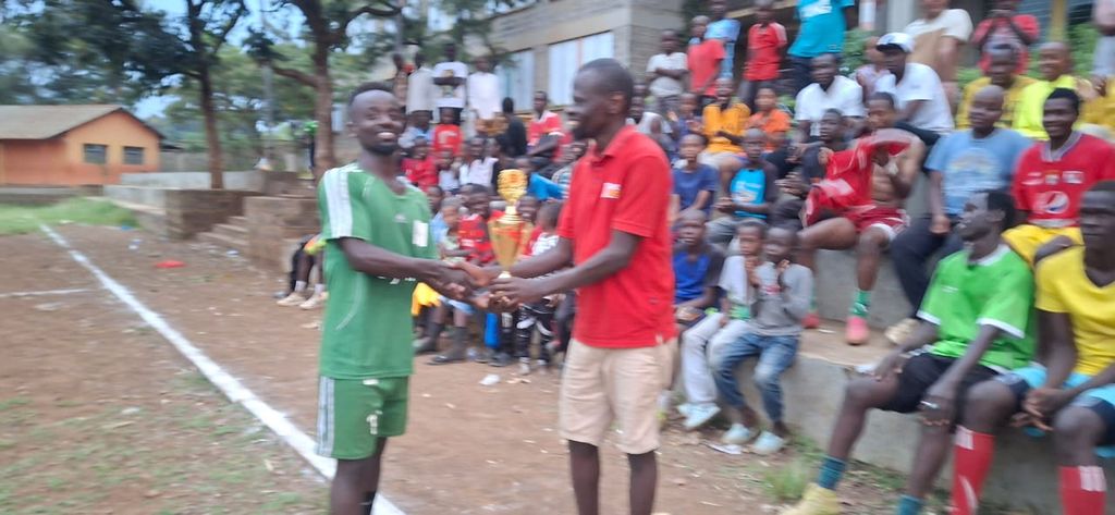 Two men shaking hands over a trophy during a prize presentation at the Inter-Masjid Football Tournament in Kisumu.